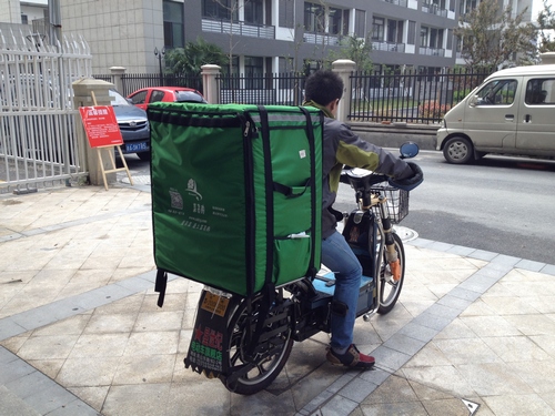 赵光明骑着电瓶车出发送菜。