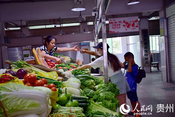 市民正在贵阳红岩农贸综合市场购买蔬菜。