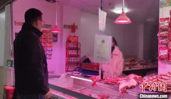 图为郑州一家农贸市场内，市场监管人员在对销售羊肉的商户逐一检查。　赵晖 摄