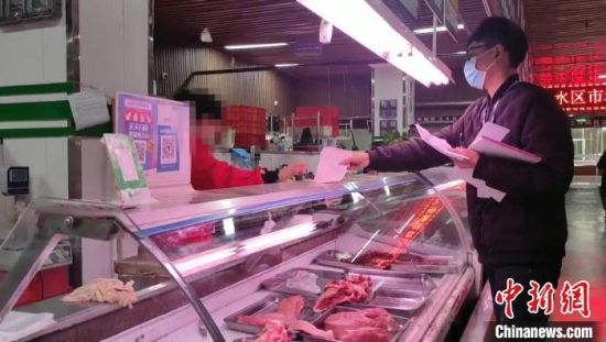 　图为郑州一家农贸市场内，市场监管人员在对肉品经营商户逐一检查。　赵晖 摄